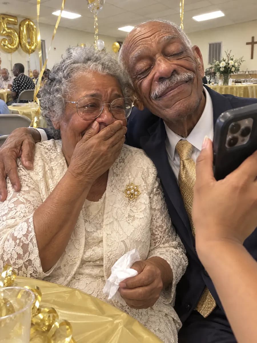 A mother covering her mouth with happy tears while she and her husband listen to a song on their daughter's phone at their 50th anniversary party